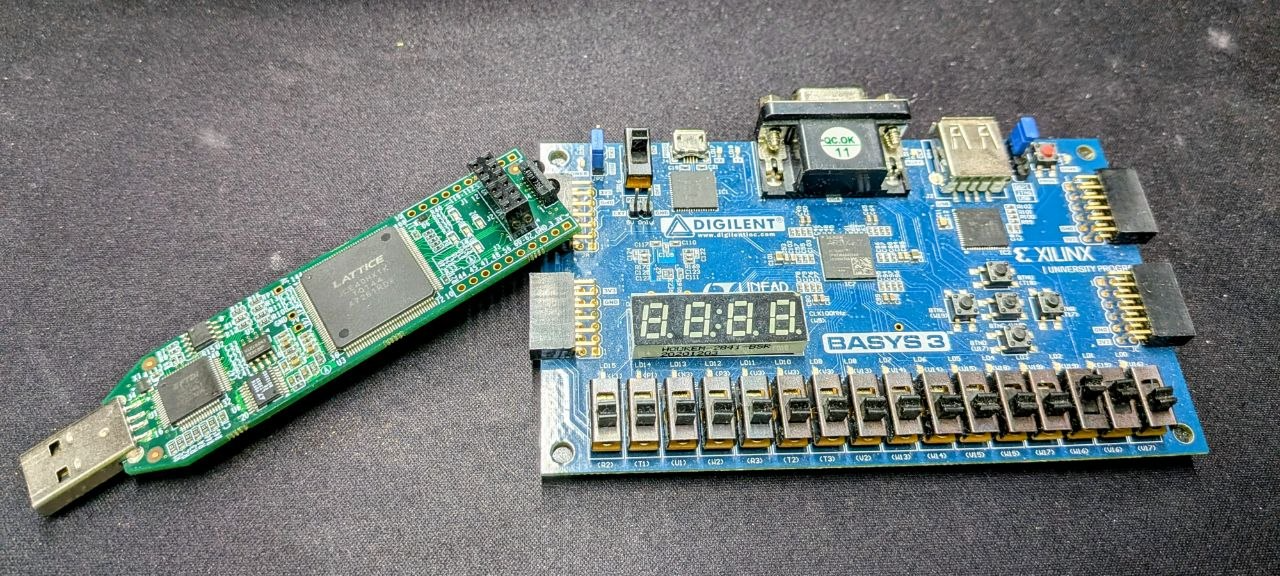 A Lattice iCEstick USB dongle next to a Digilent Basys3 development board: two ends of the FPGA beginner spectrum, from a 25-euro USB stick to a full Artix-7 board with switches, seven-segment displays, and Pmod connectors